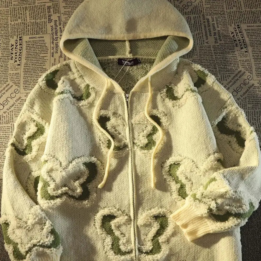 un pull blanc orné de fleurs vertes et blanches