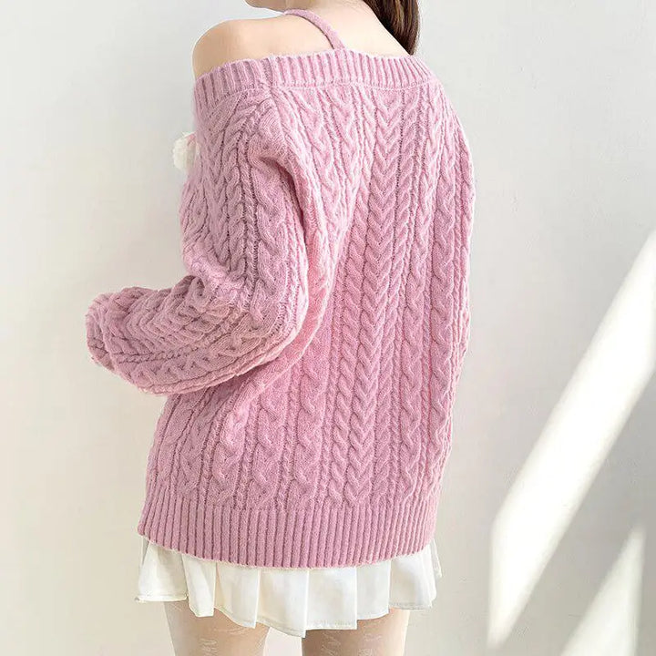 Soft pink knit sweater with cut-out shoulders and pompom details